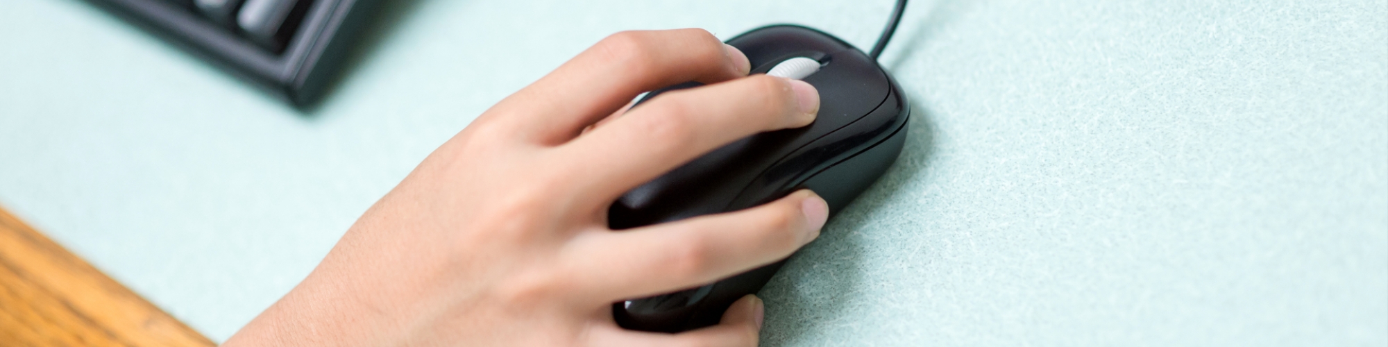 A young student's hand on an external mouse