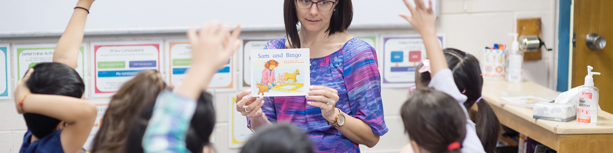 A teacher reads to students sitting around her. 