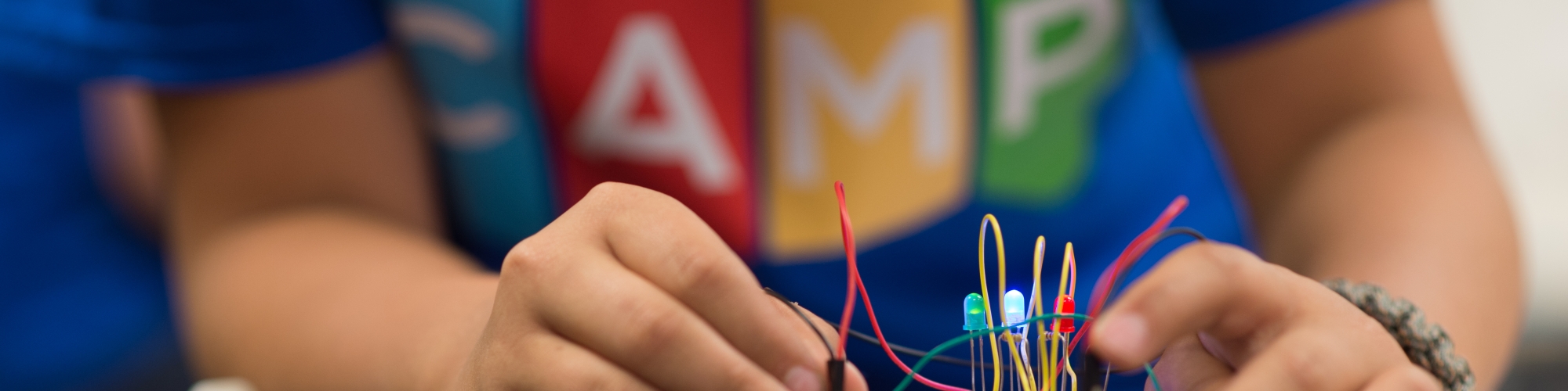 Student in blue shirt creating a circuit on a circuit board