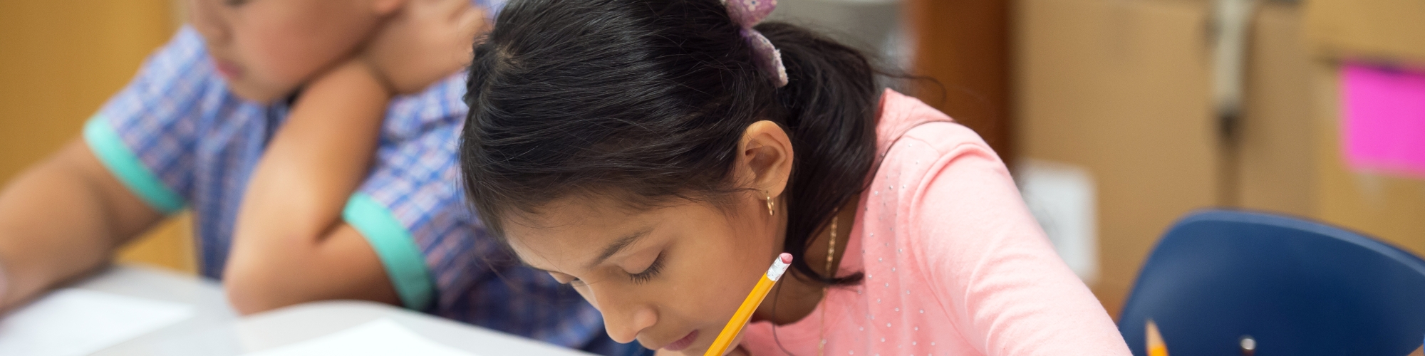 female student sitting at a desk beside other students taking a test