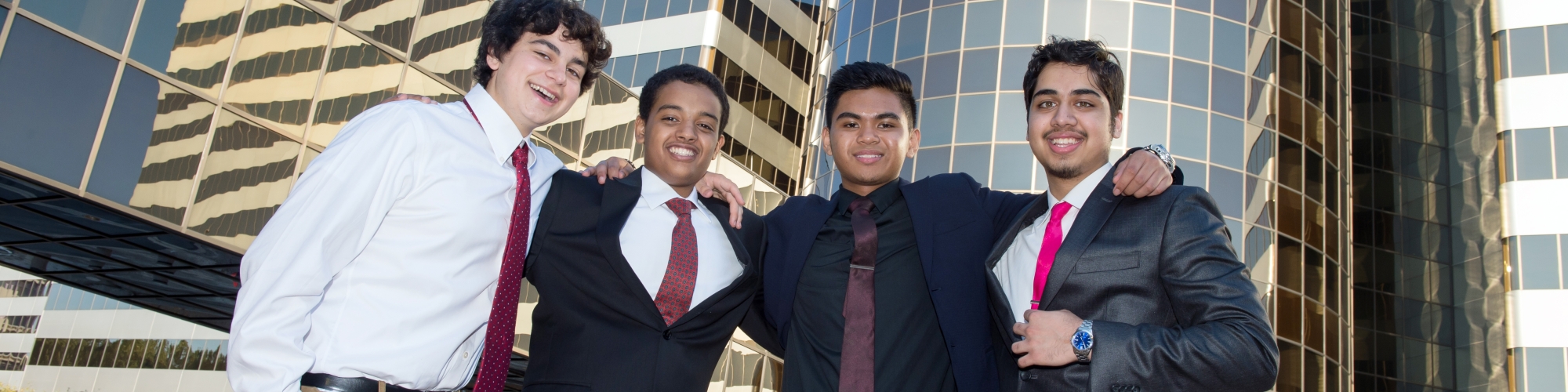 a group of four teenage boys dressed in suits standing in front of buildings