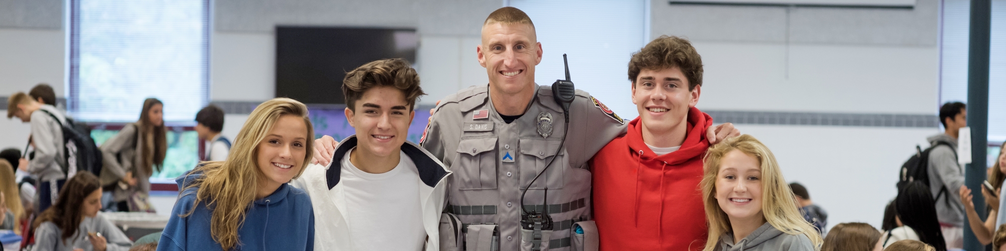 Image of a School Resource Officer standing in a cafeteria with four students