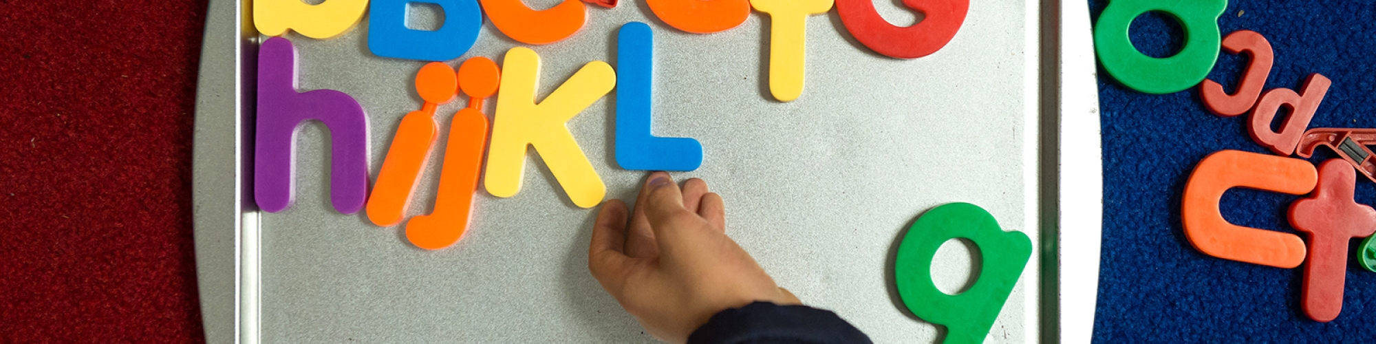 a hand rearranging magnetic letters on a tray