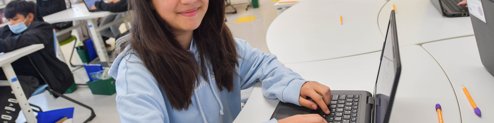 female student typing on laptop in classroom