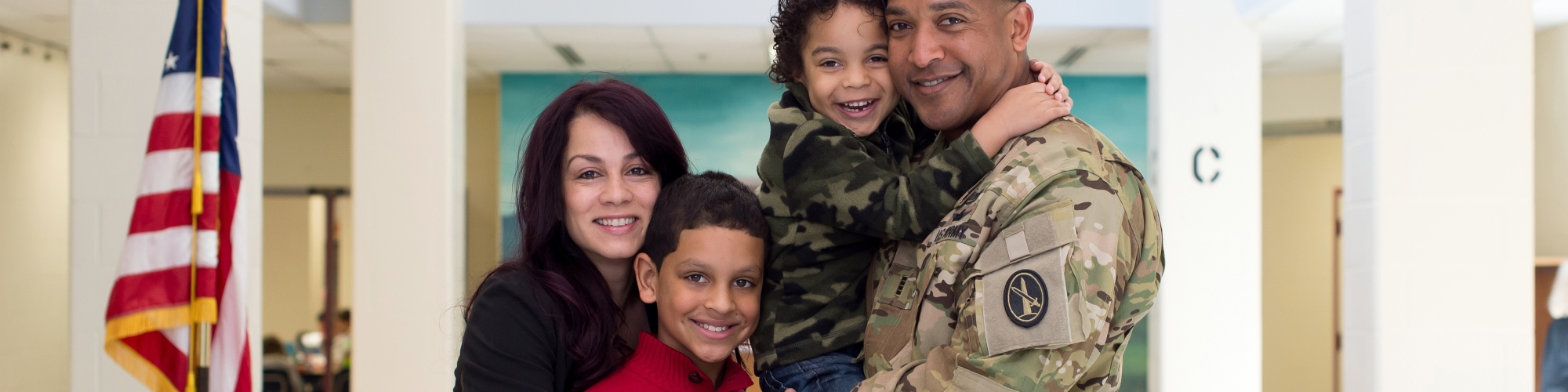 a family standing together smiling with dad in a military uniform
