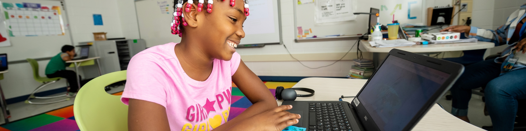 girl smiling at table with laptop