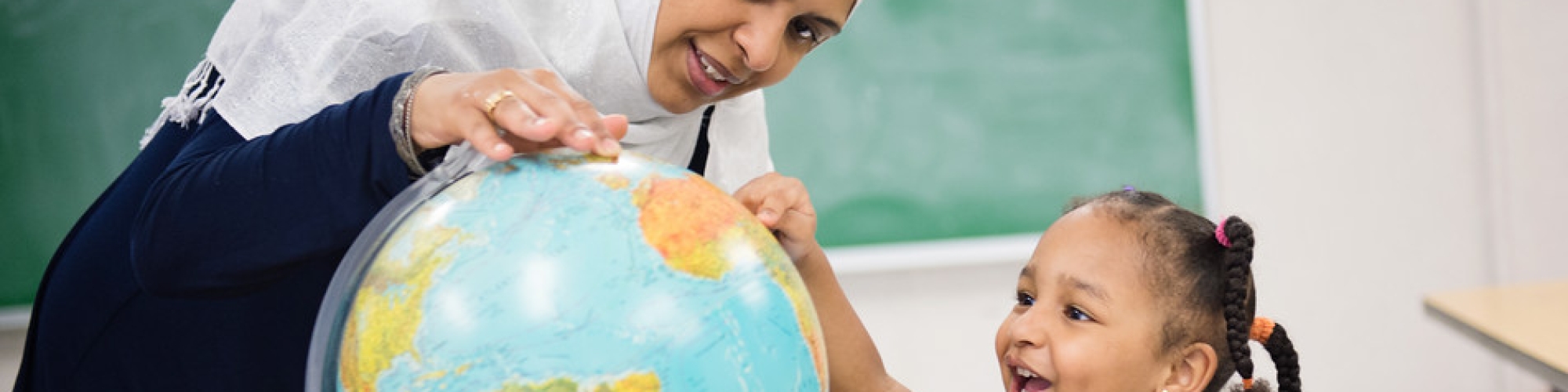 adult and child looking at globe