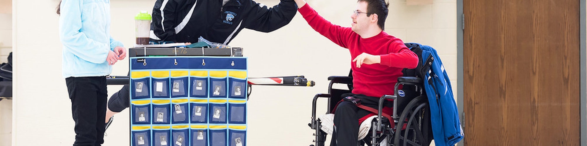 a student in a wheelchair giving a teacher a high five 
