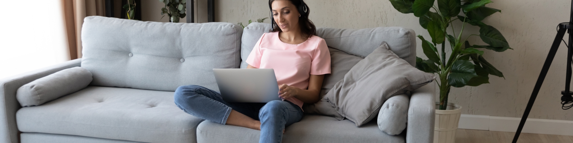 woman sitting on the couch with a laptop and headphones