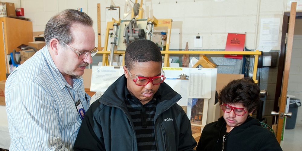 students working with teacher in technical education class